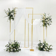 White rose wedding backdrop with greenery, gold rectangular metal frames and flowing white drapes